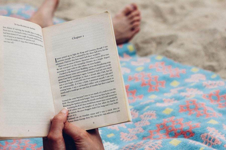 Person reading on the beach, book opened to Chapter 1.